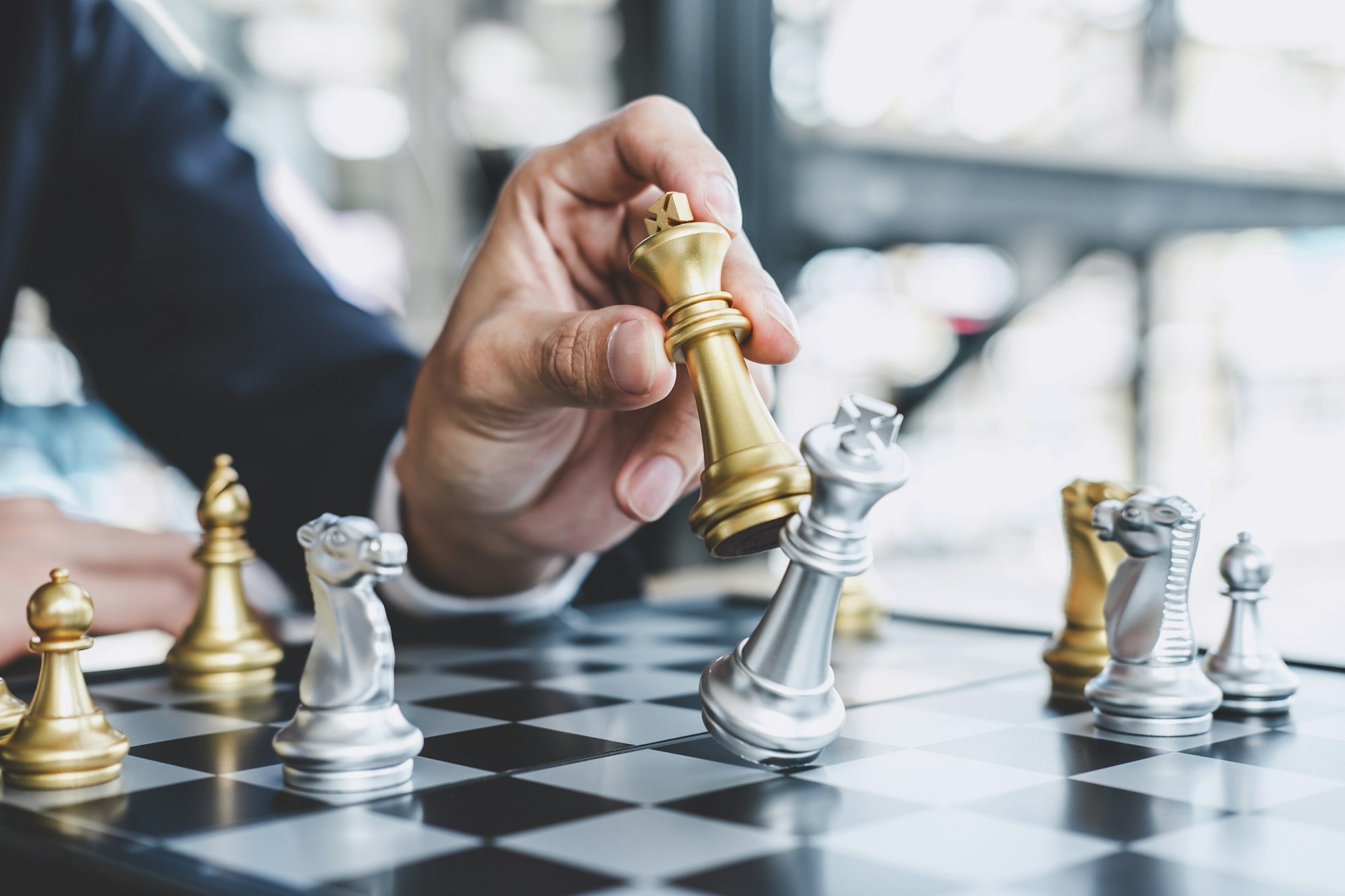 Businessman playing chess game reaching to plan strategy for success, thinking for planning