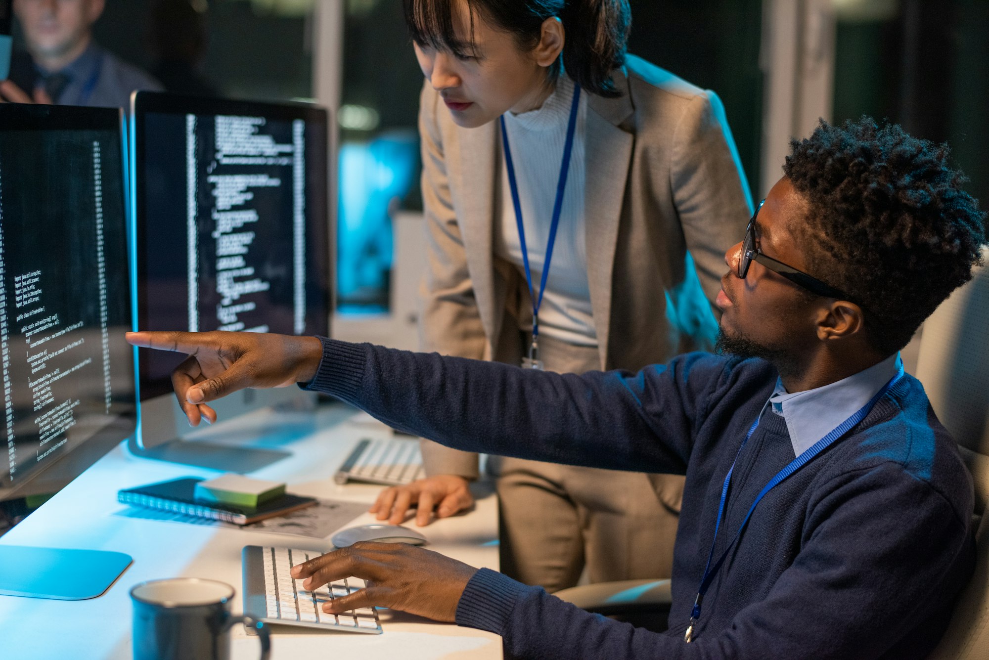 Two young intercultural colleagues discussing coded data